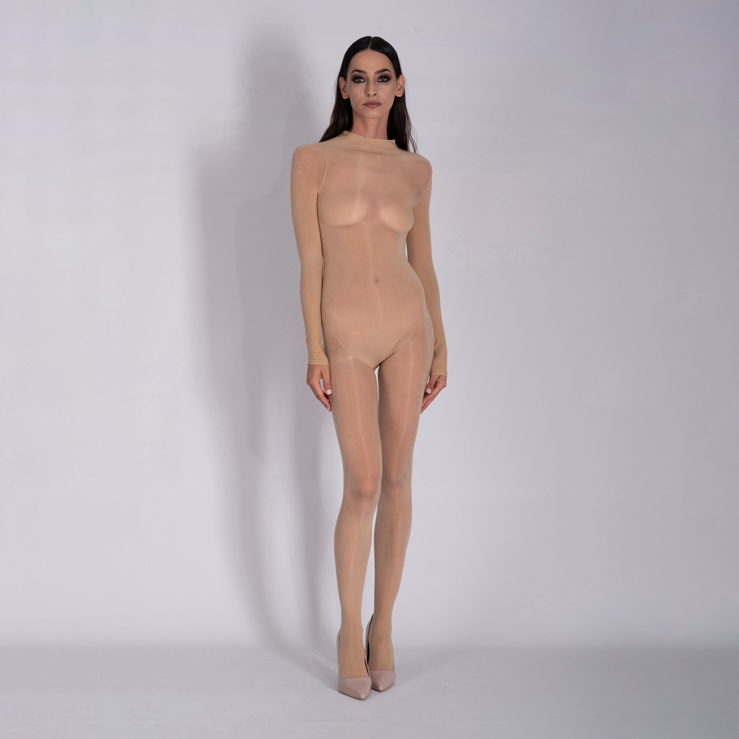 Person wearing a sheer beige bodysuit against a white background