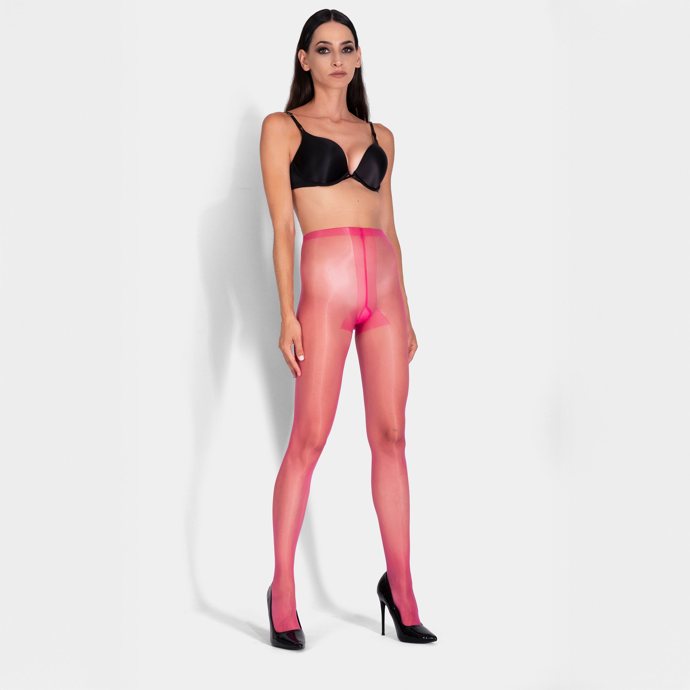 Woman wearing pink sheer stockings and a black bra on a white background